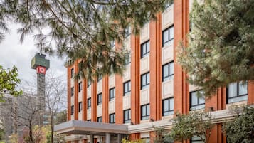 A multi-story building with a brick facade, large windows, and a covered entrance area.