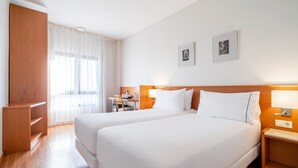 Una habitación de hotel con dos camas, un escritorio, una silla y un armario.