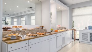 Una cocina moderna con una encimera larga que exhibe diversas opciones de panadería y pastelería.