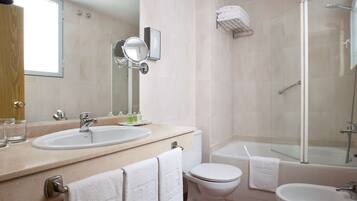 A modern bathroom with two sinks, a toilet, a bidet, and a glass-enclosed shower.