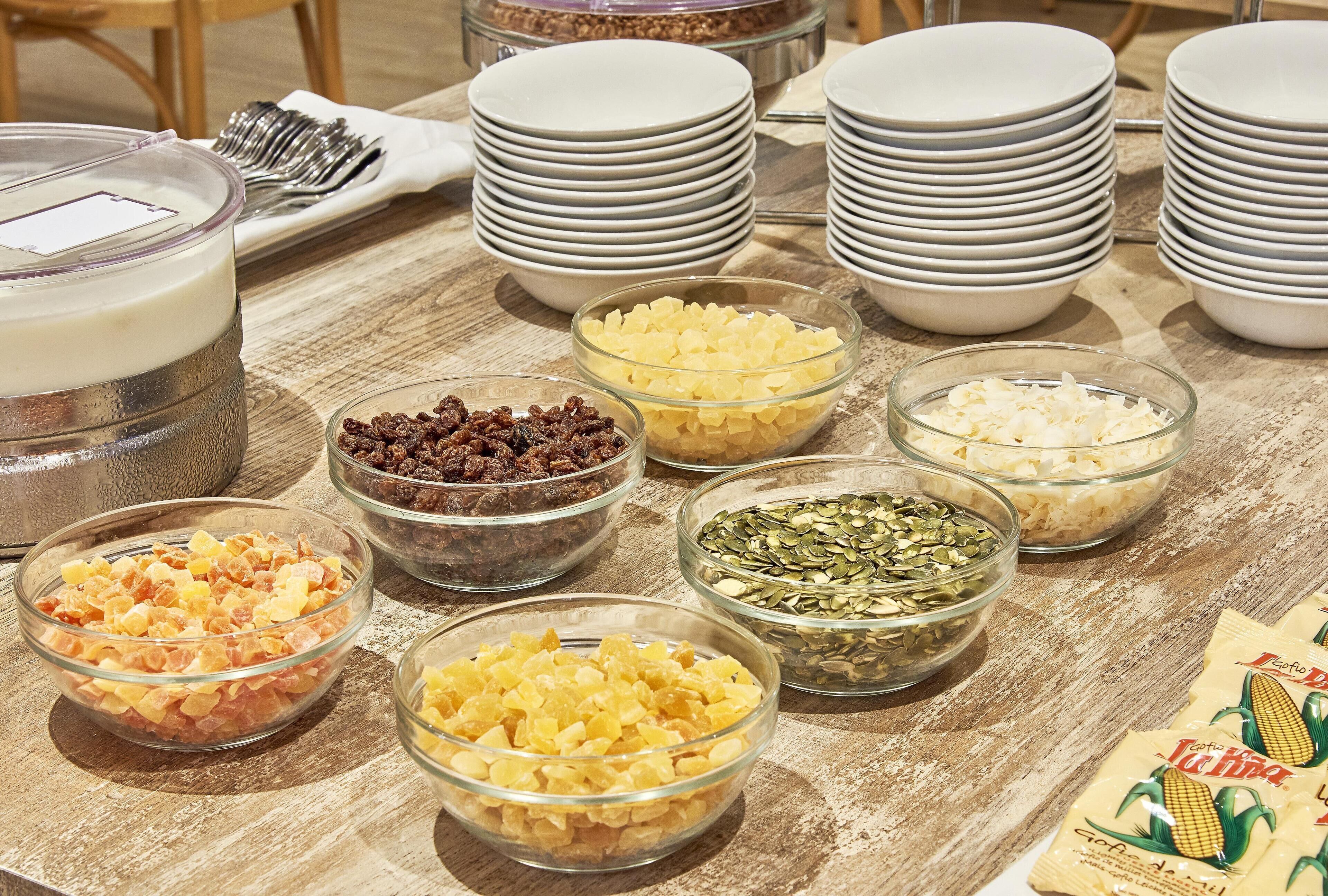 Une table de buffet garnie de divers plats et sur laquelle sont empilées des assiettes blanches.
