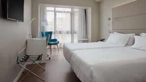 A hotel room with two beds, a desk with a chair, a TV, and a window with curtains. - NH Las Palmas Playa las Canteras (Las Palmas de Gran Canaria)