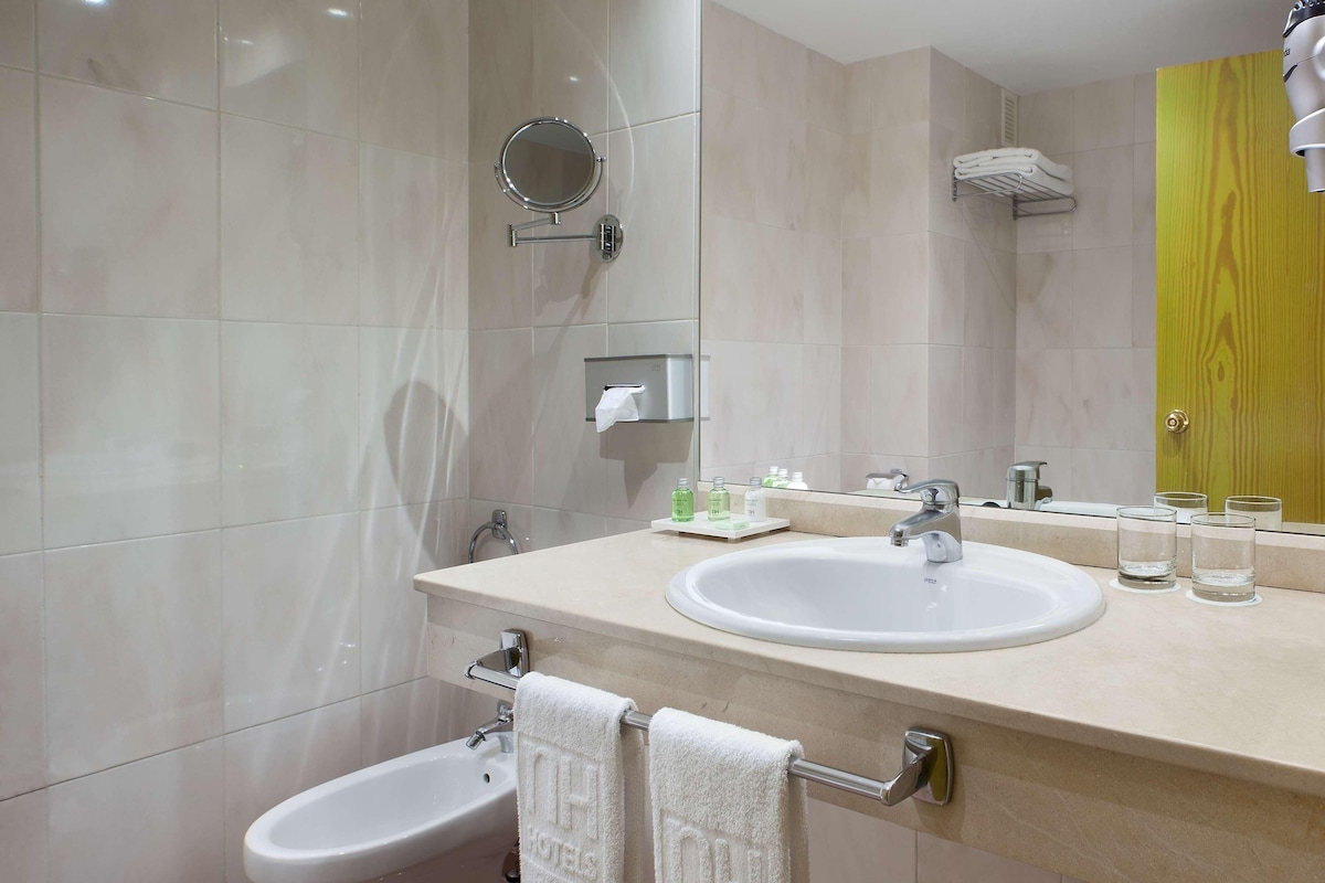 Une salle de bain moderne équipée d’un bidet, d’un lavabo, d’un miroir et d’un porte-serviettes.