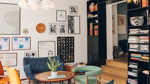 A modern living room with a round coffee table, comfortable seating, a bookshelf, and a variety of framed pictures and decorative items on the walls. - Hotel Alexandra (Copenhagen)
