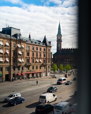 Katunäkymä, jossa näkyy rakennuksia, kellotorni ja ajoneuvoja.