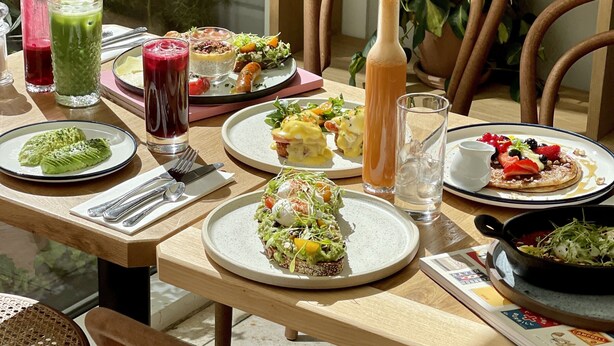 A dining table with various dishes, drinks, and a book. - Hotel Alexandra (Copenhagen)
