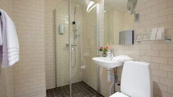 Un baño con ducha de vidrio, lavamanos blanco y un inodoro.