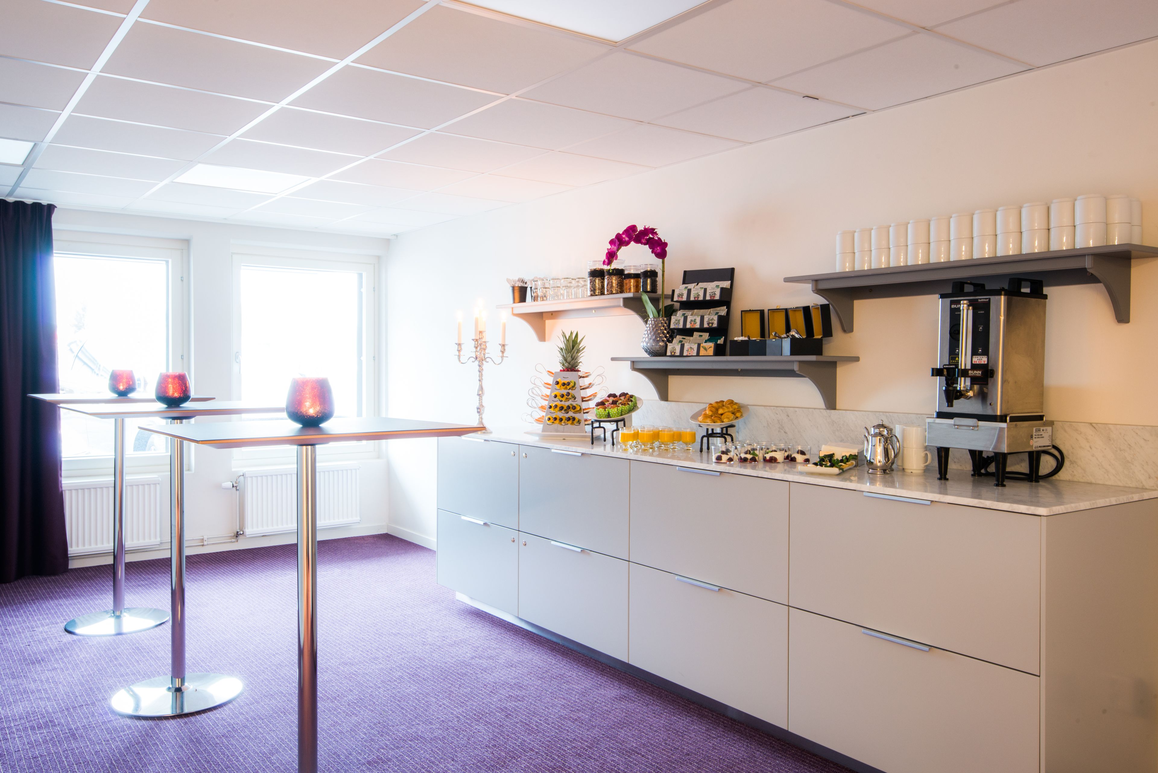 A modern kitchen with a marble countertop, a coffee machine, and various food items.