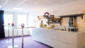 A modern kitchen with a marble countertop, a coffee machine, and various food items.