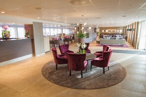 A hotel lobby with a reception desk, seating area with chairs, a sofa, and a large potted plant. - Best Western Arlanda Plus Park Airport Hotel (Arlandastad)