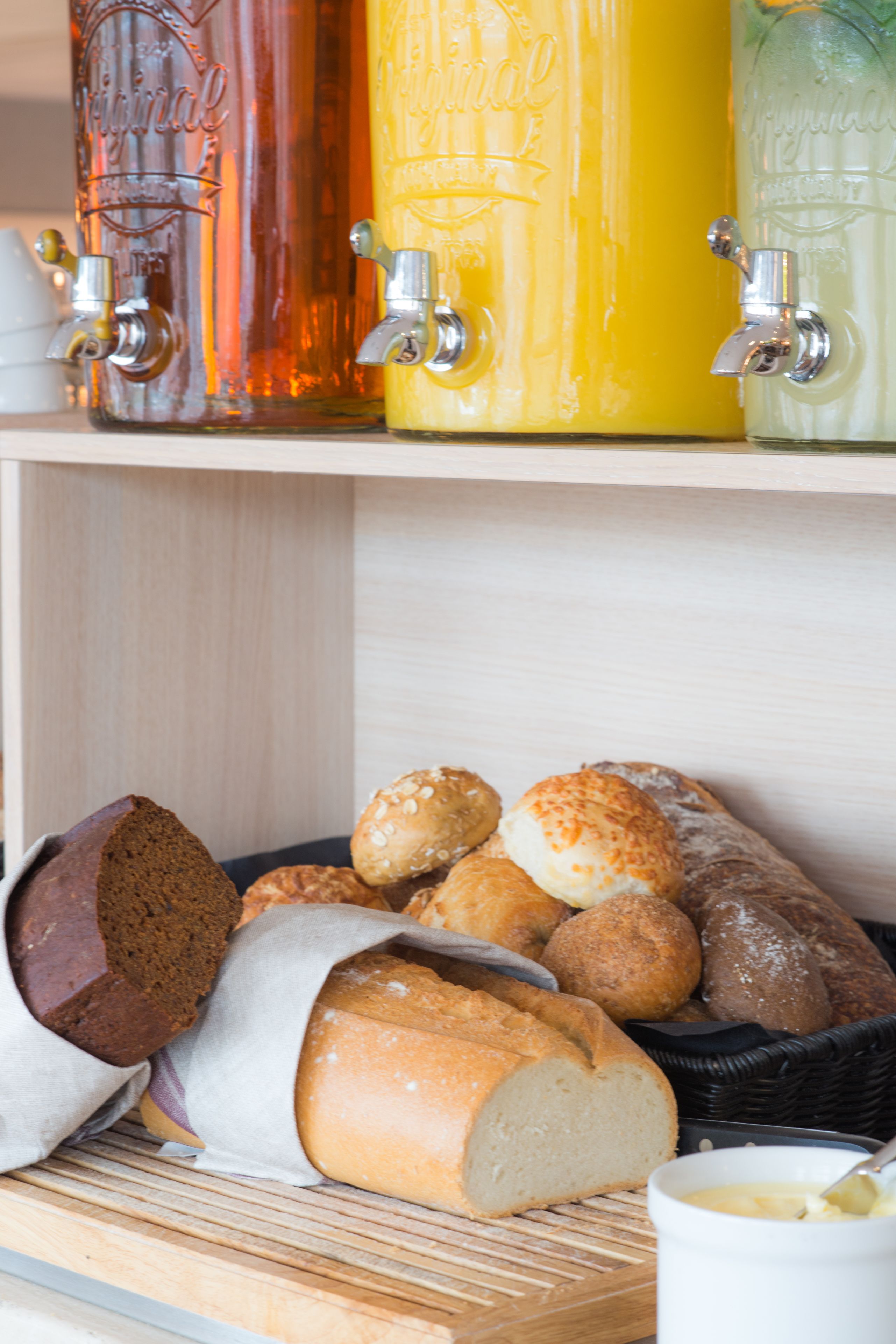 A wooden shelf with various bottles and a basket of bread.