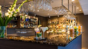 A bar area with a marble countertop, shelves of liquor bottles, and hanging glassware. - Best Western Arlanda Plus Park Airport Hotel (Arlandastad)