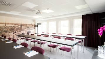 A conference room with a long table, multiple chairs, and a projector screen.