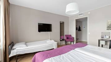 Habitación de hotel con dos camas individuales, televisión, espejo, una silla y escritorio con lámpara.