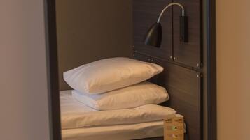 A compact room with a bed, a small table, and a wall-mounted lamp.