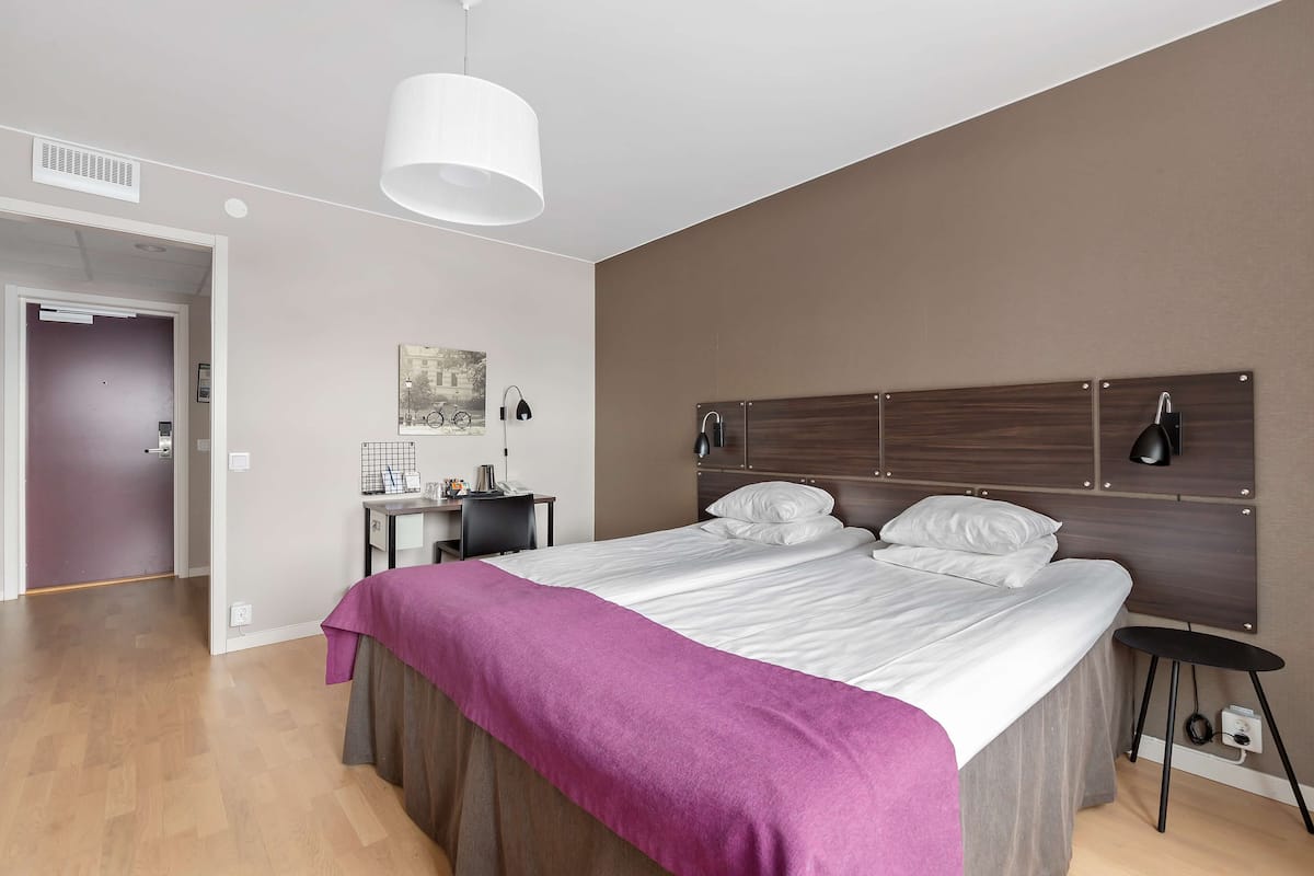 A modern bedroom with a large bed, a desk, and a chair.