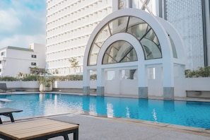 Un hôtel moderne doté d’une grande piscine, d’un espace salon abrité et d’une structure en verre arquée remarquable.