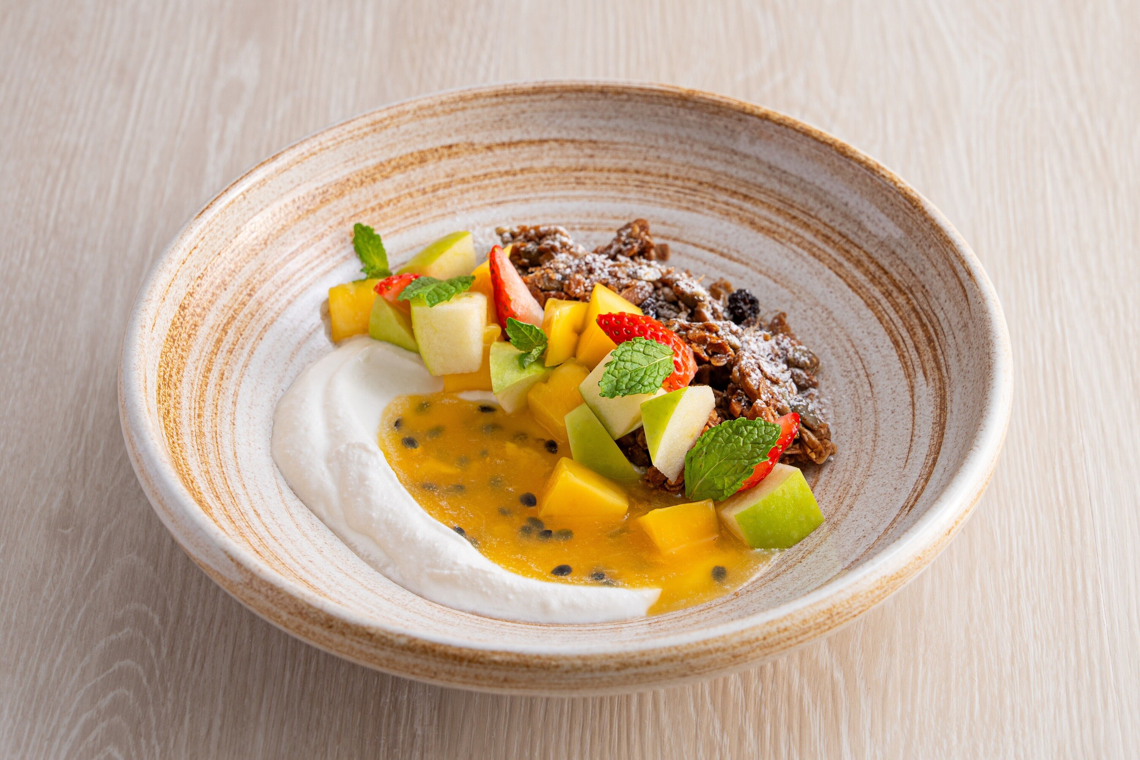 A dessert in a ceramic bowl with fruit and a creamy base.