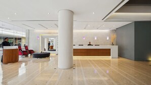 A modern hotel lobby with a reception desk, seating area, and a large pillar. - BelAire Bangkok Sukhumvit (Bangkok)