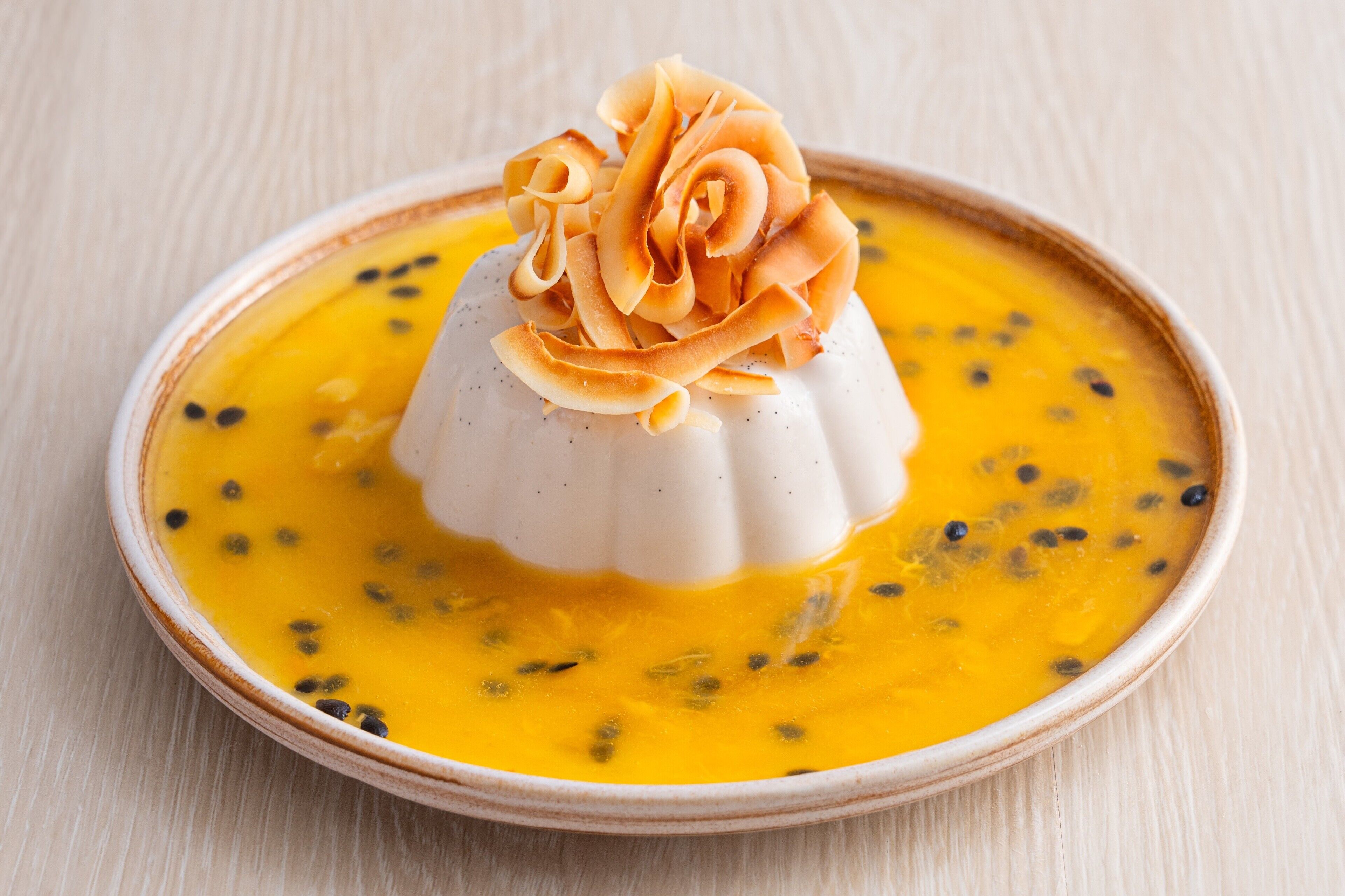 Ein Dessert mit weißer Basis und gelber Soße, garniert mit karamellisiertem Obst.