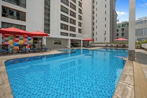 A swimming pool with tiled flooring, lounge chairs, and umbrellas. - BelAire Bangkok Sukhumvit (Bangkok)