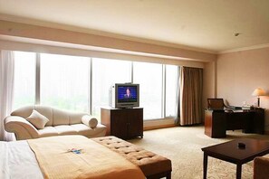 A hotel room with a bed, a sofa, a television, a desk, and a lamp. - Beijing Continental Grand Hotel (Beijing)