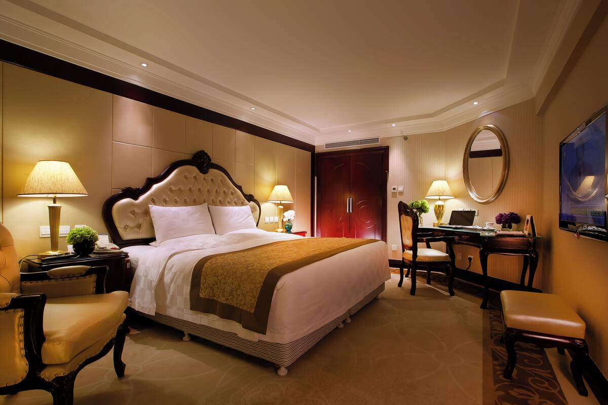 Une chambre d’hôtel spacieuse, dotée d’un grand lit, d’un bureau, d’une chaise et d’un miroir.