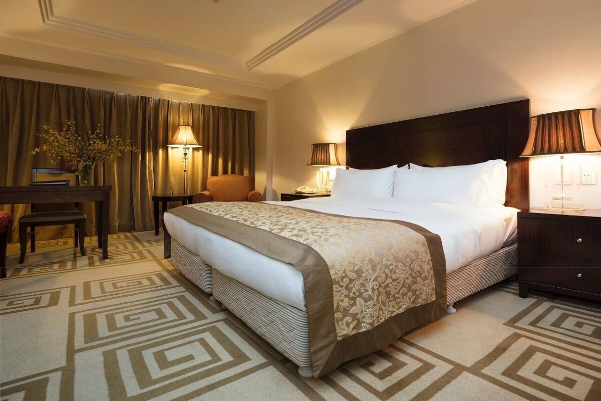 Une chambre d’hôtel avec un grand lit, deux tables de chevet, un bureau, une chaise et une lampe.