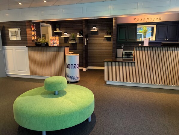 Welcome to the reception area, where guests can check in and enjoy a comfortable seating area with a table and lamp.