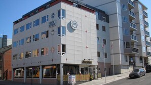 Un hôtel moderne, avec plusieurs étages, de grandes fenêtres et un logo bien visible.