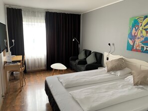 Relax in a spacious room with a large bed, desk, and comfortable armchair.