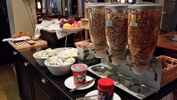 Un buffet de petit-déjeuner proposant une variété d’aliments, notamment des céréales, du yaourt et du Nutella.