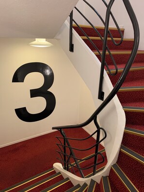 Stunning spiral staircase with a striking black number '3' on a prominent wall.
