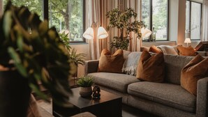 Ein modernes Wohnzimmer mit einem grauen Sofa, mehreren Kissen, einem Couchtisch mit einer Pflanze und zwei Stehlampen.