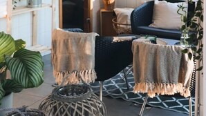 Ein gemütliches Zimmer mit Holztür, gepolstertem Sitz und hängenden Pflanzen.