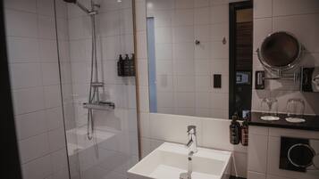 A modern bathroom with a glass-enclosed shower, a white sink, and a mirror with a round frame.