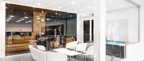 Egy modern irodai tér üvegfalakkal, fehér bútorokkal és egy úszómedencével, amely az üvegfalakon keresztül látható.