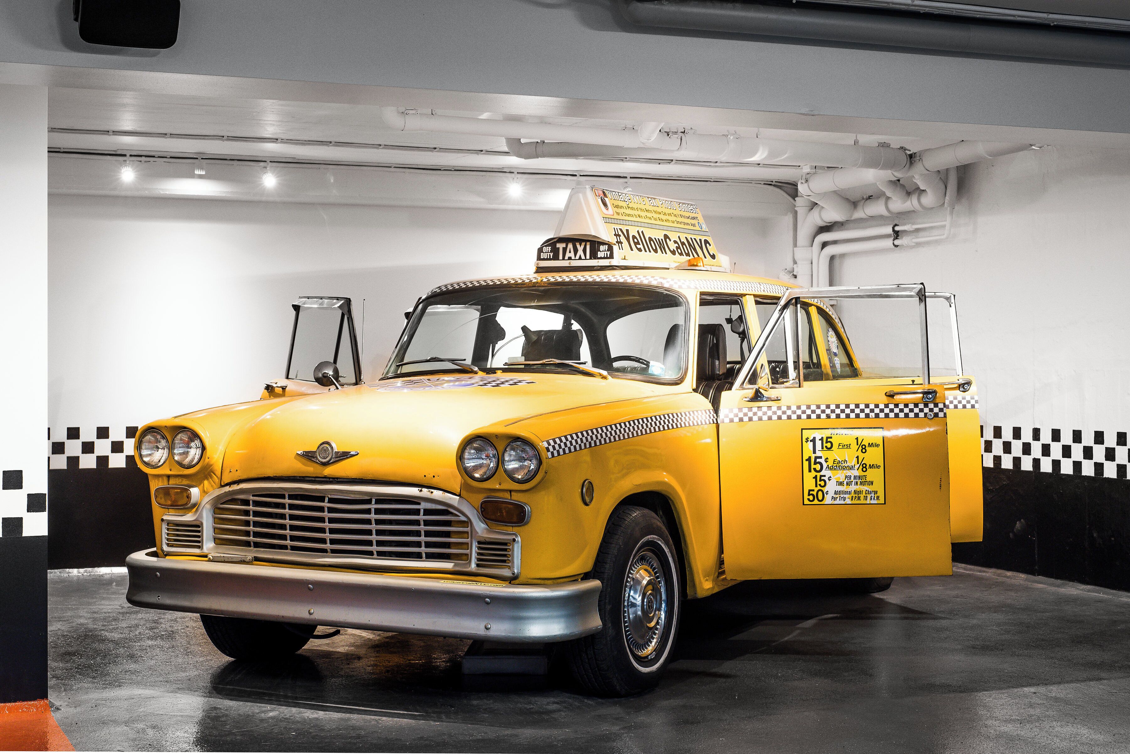 Un taxi amarillo con un estampado a cuadros en la lateral, estacionado en un garaje.