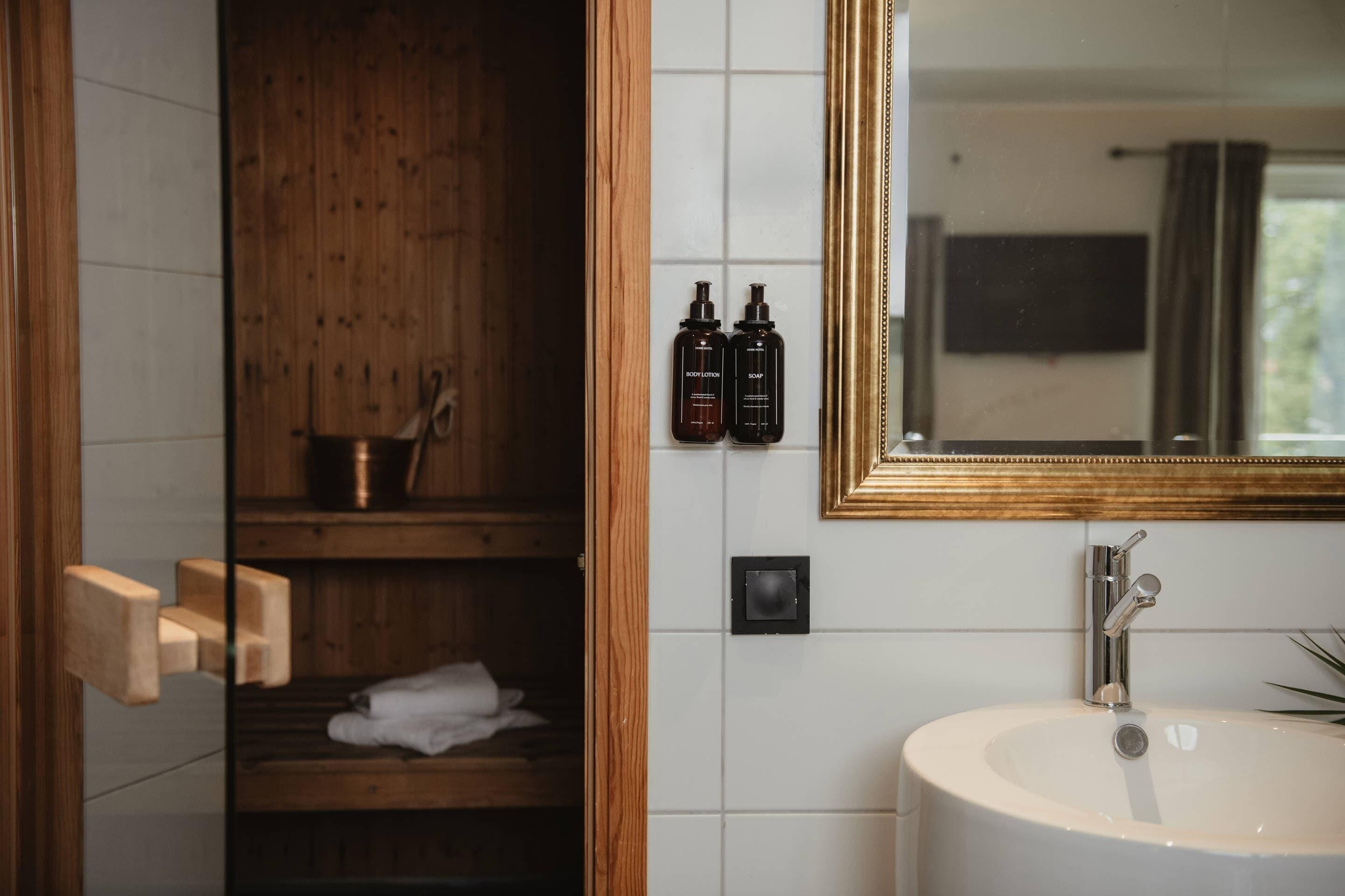 A bathroom with a wooden shelf, a white sink, and two bottles of body lotion.