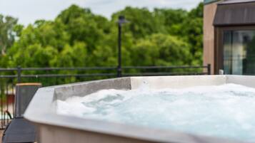A hot tub with a view of lush green trees in the background.