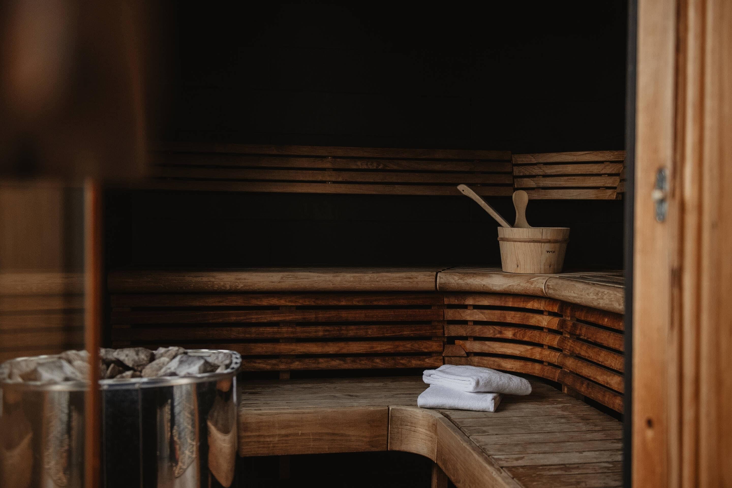 Un sauna avec des bancs en bois et un récipient en métal, probablement destiné aux serviettes.