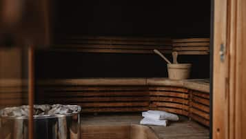 Un sauna avec des bancs en bois et un récipient en métal, probablement destiné aux serviettes.