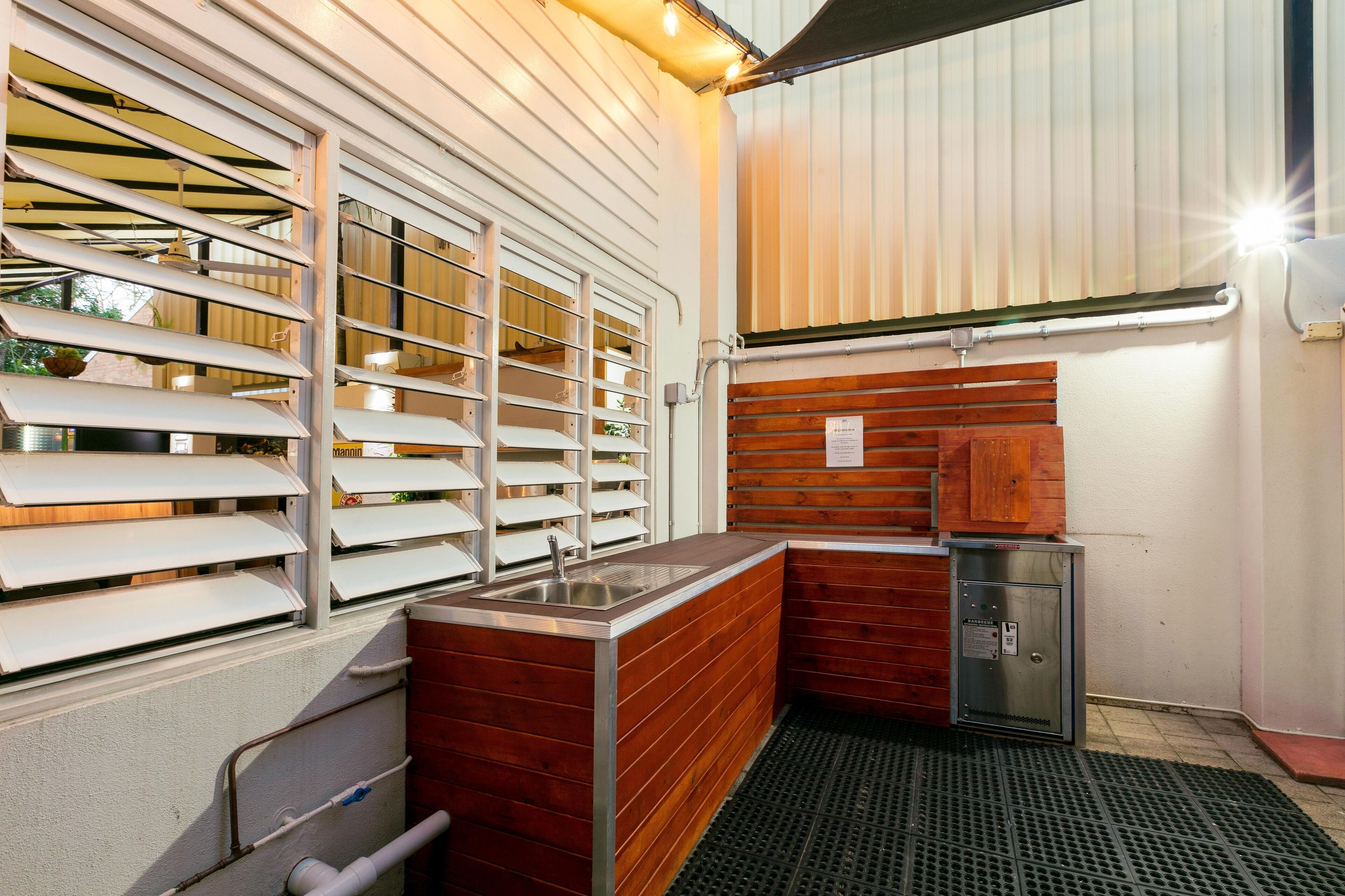 A compact kitchen with a sink, wooden cabinets, and a built-in refrigerator.