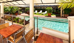 Una piscina al aire libre, sillones reclinables de piscina