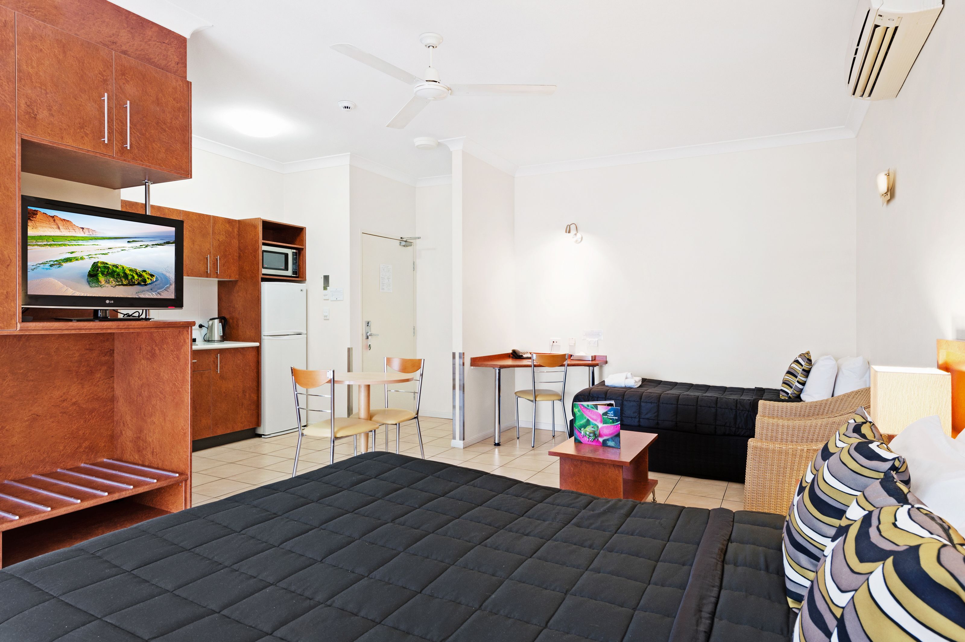 Habitación de hotel con cama, escritorio, sofá, televisión y kitchenette.