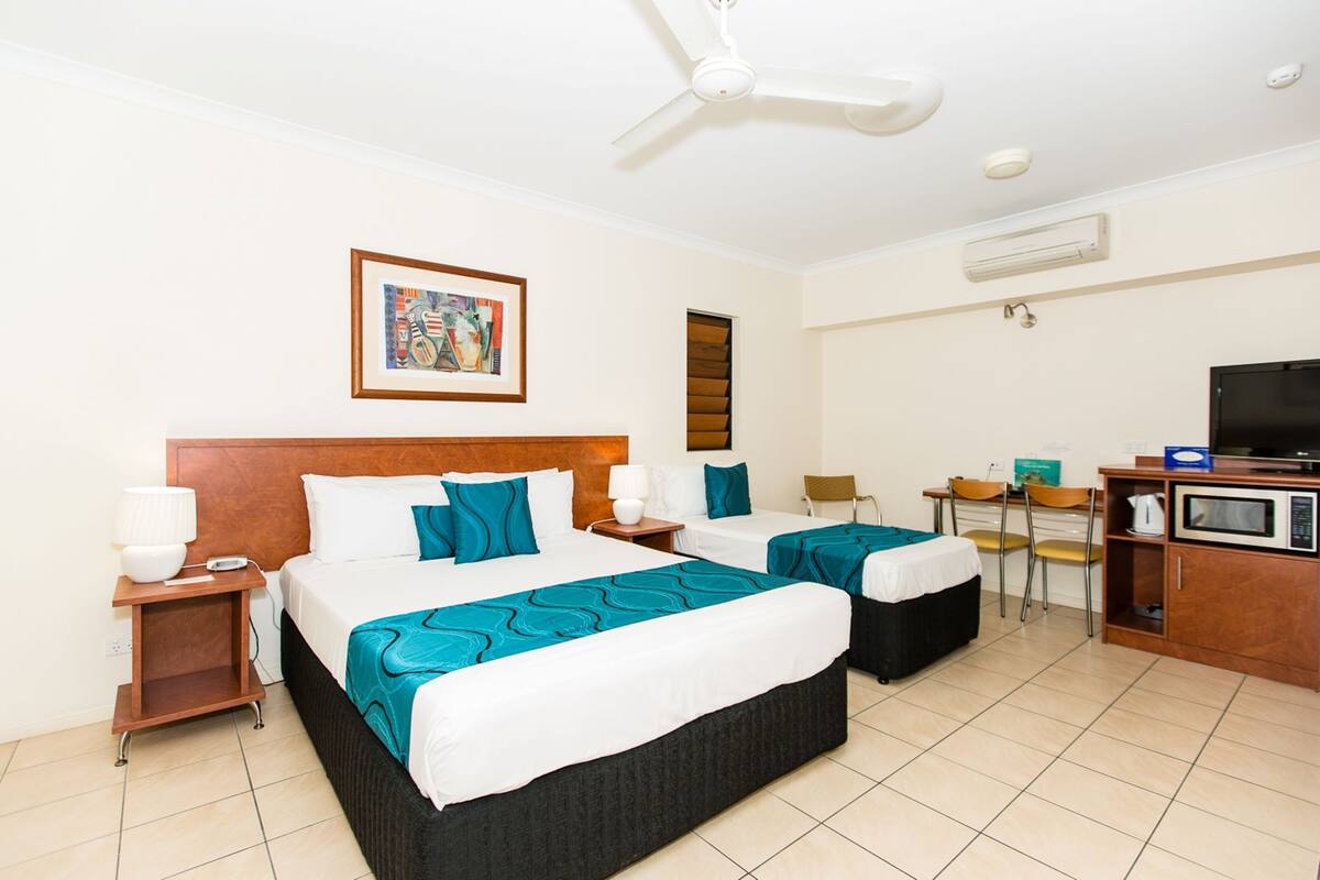 Une chambre d’hôtel avec deux lits, une télévision, un four à micro-ondes et un petit coin repas.