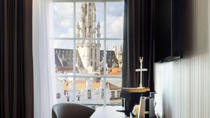 Une chambre d’hôtel dotée d’une grande fenêtre donnant sur un bâtiment historique à l’architecture complexe.
