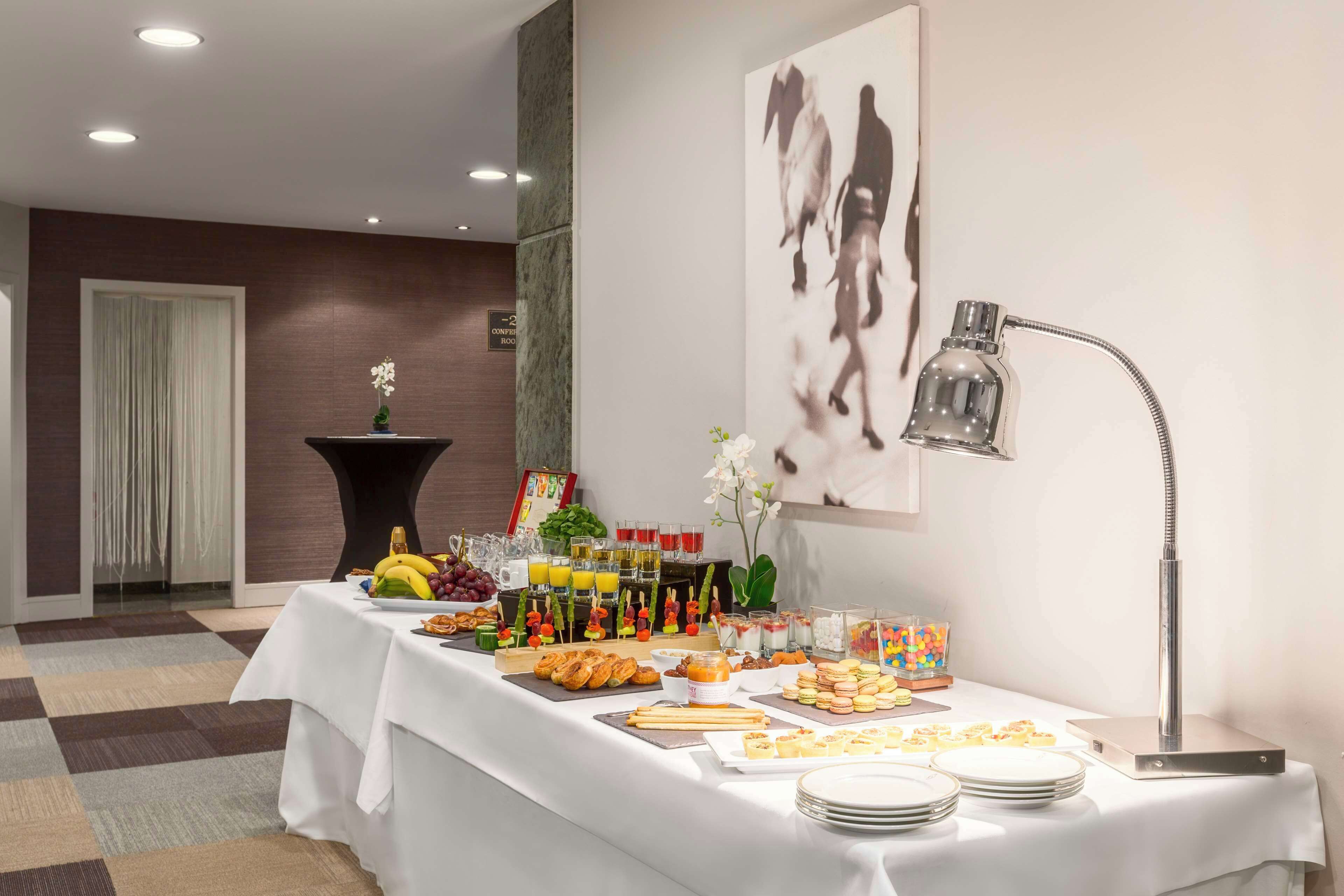 A buffet table with various food items and drinks, a large abstract painting, and a modern lamp.