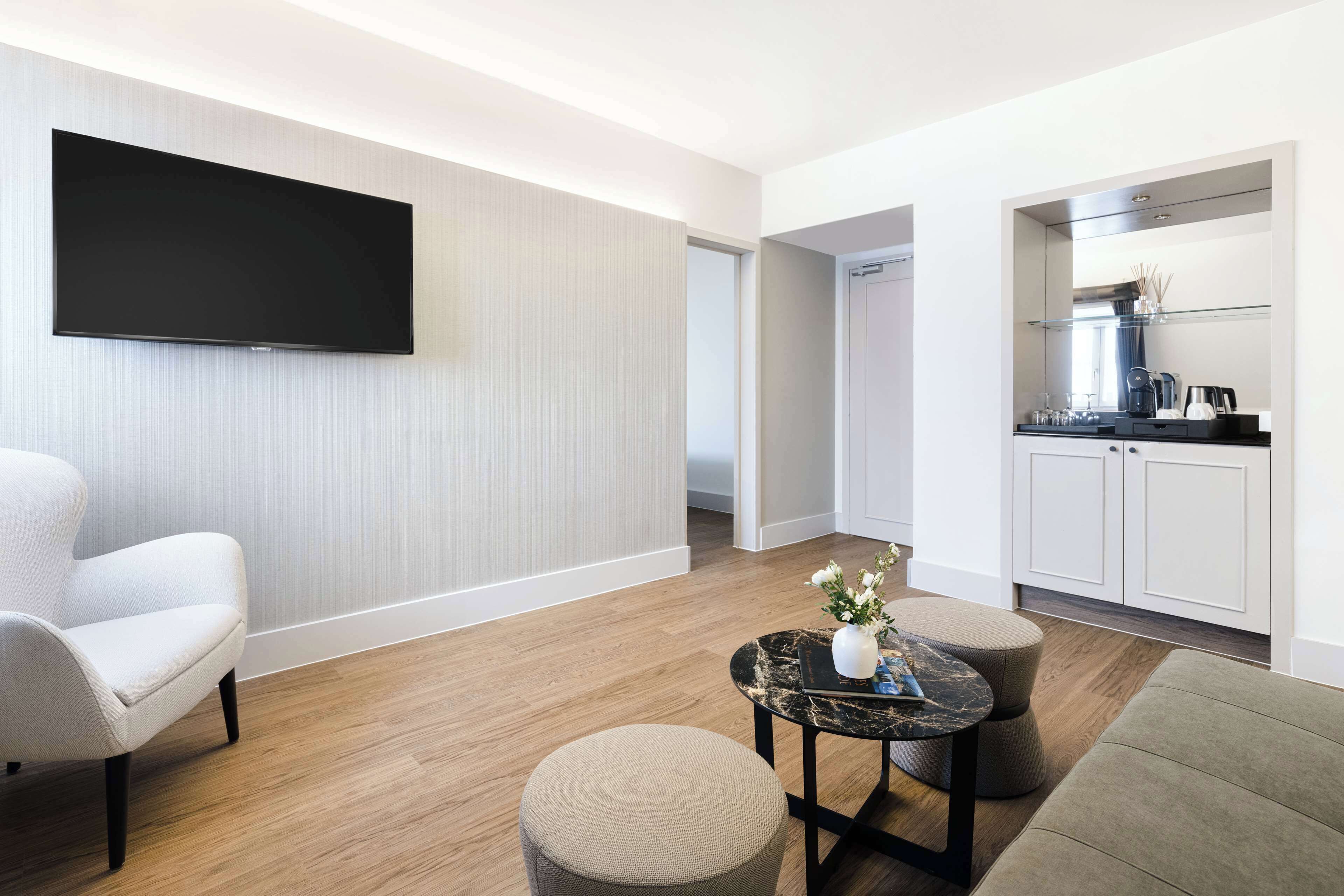 Una sala de estar moderna con un televisor de pantalla plana, un sofá, una mesa de centro y una zona de cocina con armarios y una encimera.