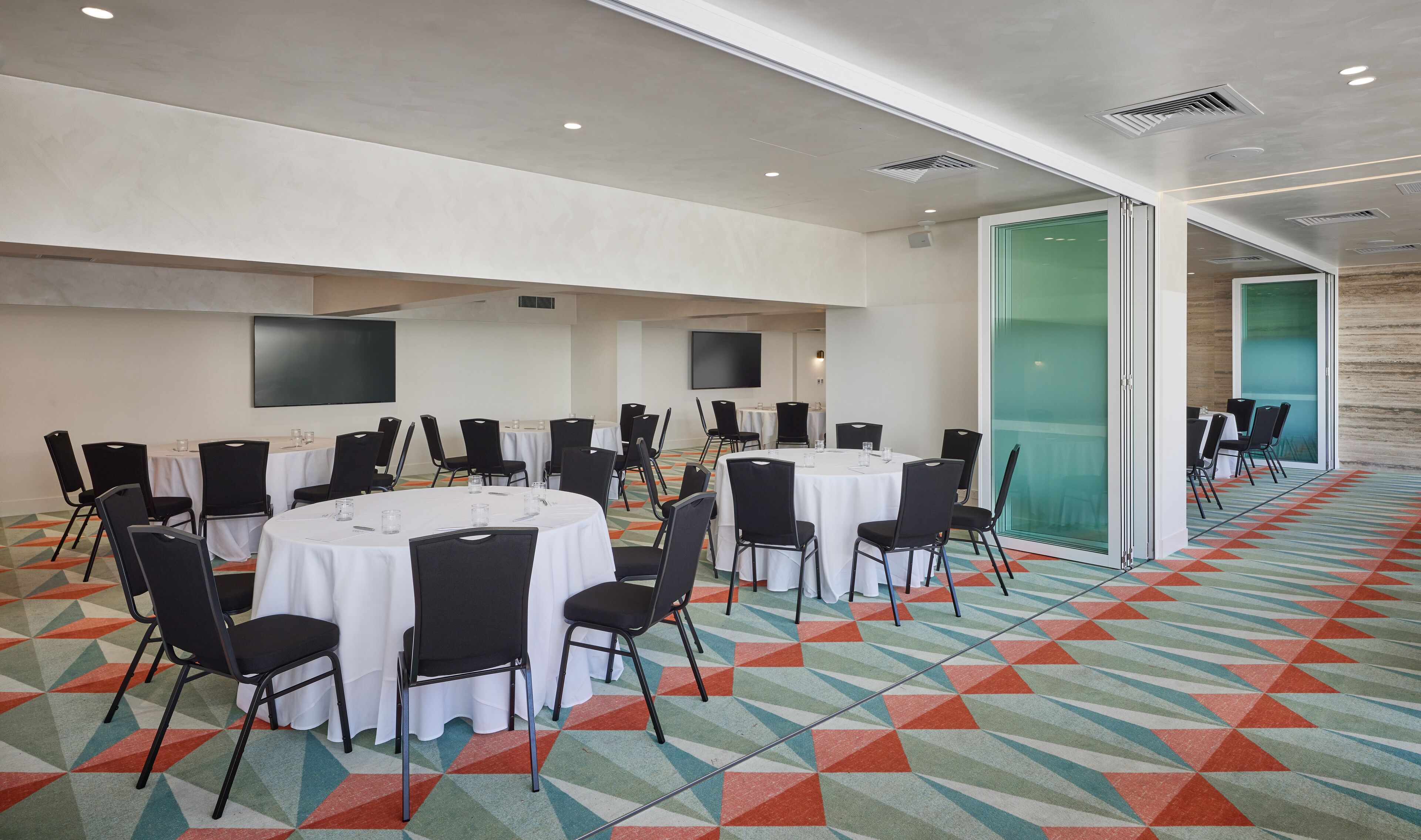 A conference room with round tables, black chairs, and a colorful geometric carpet.